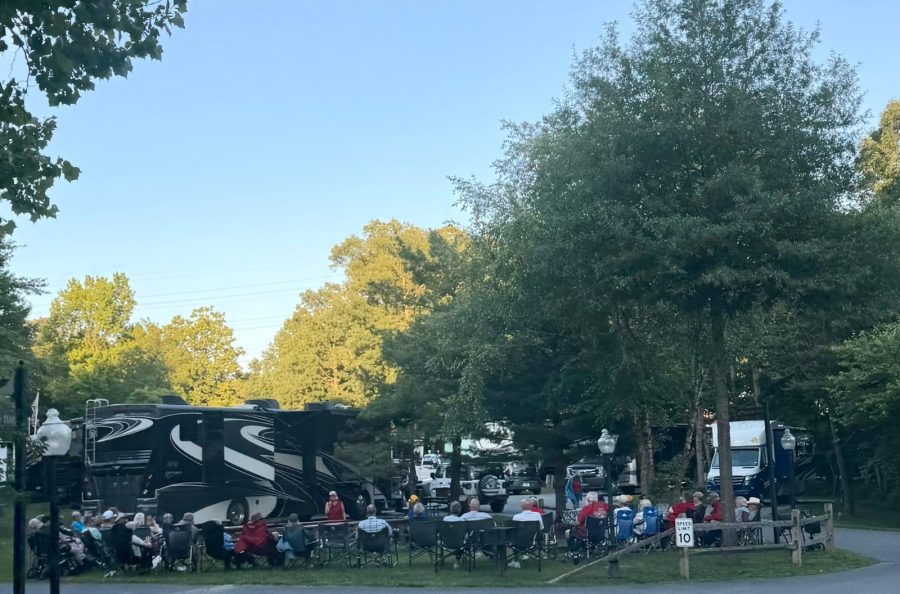 A large RV caravan group gathered in a circle of camp chairs at Cherry Hill Park