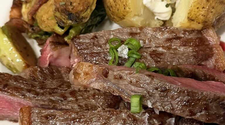 Sliced steak with baked potato and roasted Brussels sprouts made in our RV