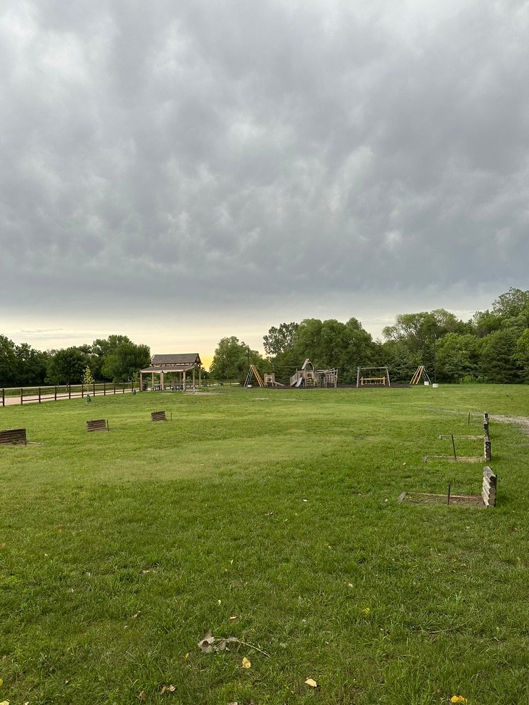 Open grassy park grounds at Ravenna Lake under a cloudy Nebraska sky