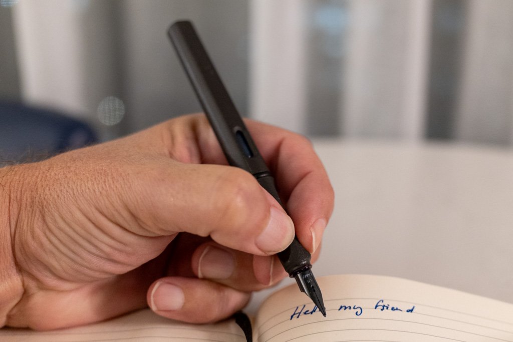 Left-handed writing in a Moleskine notebook with a black Lamy Safari fountain pen